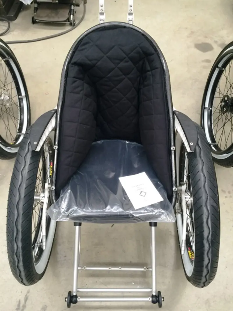 A front-facing view of the Trekinetic wheelchair with a cushioned Hyperforma seat insert.