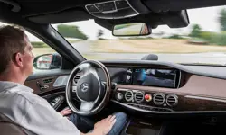 A man sitting in a moving car autonomous vehicle, with his hands on his lap.