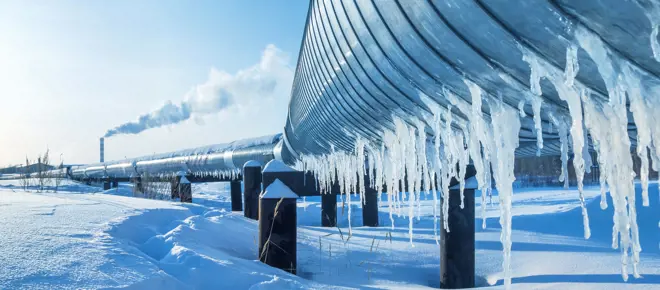 A pipeline in the snow, with icicles hanging from it. 