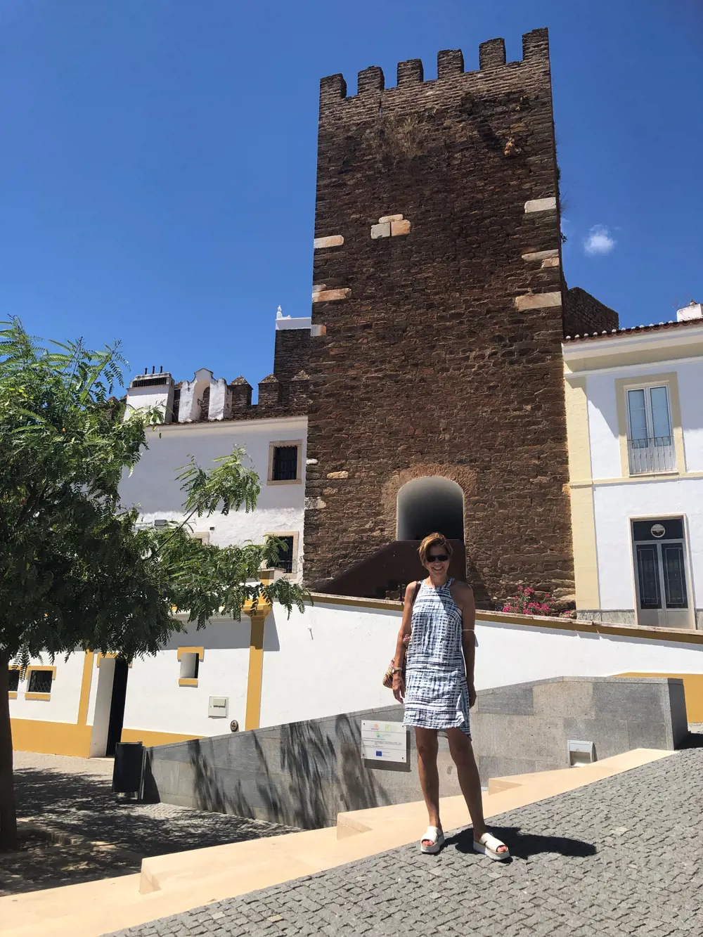 Dr Luisa Freitas dos Santos standing in front of a castle in a Portuguese town on a sunny day.