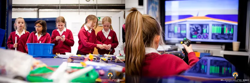 Young female students building model rocket cars (left). A young female student driving in a Bloodhound simulated driving experience (right).