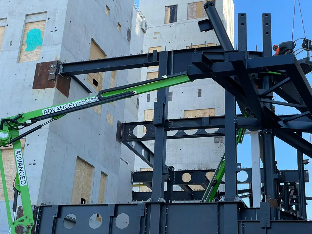Steel framework being assembled between concrete structures during construction.