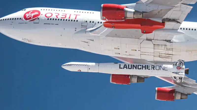 A view of the underside of the Cosmic Girl aircraft while it is in the air with the LauncherOne rocket attached underneath the aircraft wing.