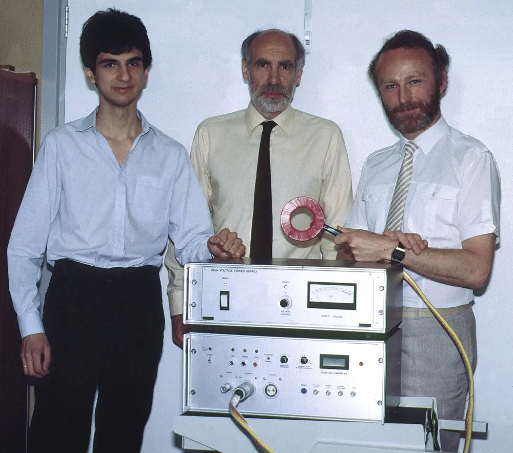 Dr Reza Jalinous, Professor Ian Freeston and Professor Tony Barker standing next to the first TMS stimulator.