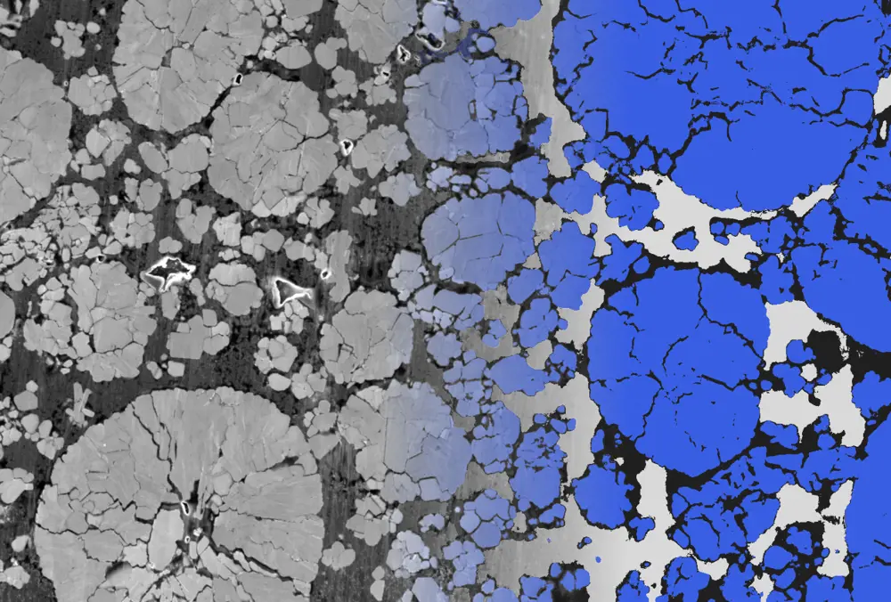 A cross section of a crystalline-looking material, packed with grains, seen in grayscale with a blue digital overlay on one side.
