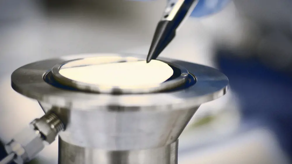 A thin graphene-oxide membrane being held on a platform with tweezers.