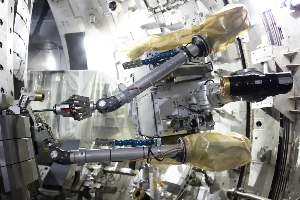 Remote handling robot in a nuclear facility. The robot has silver metal arms and has cover protection.