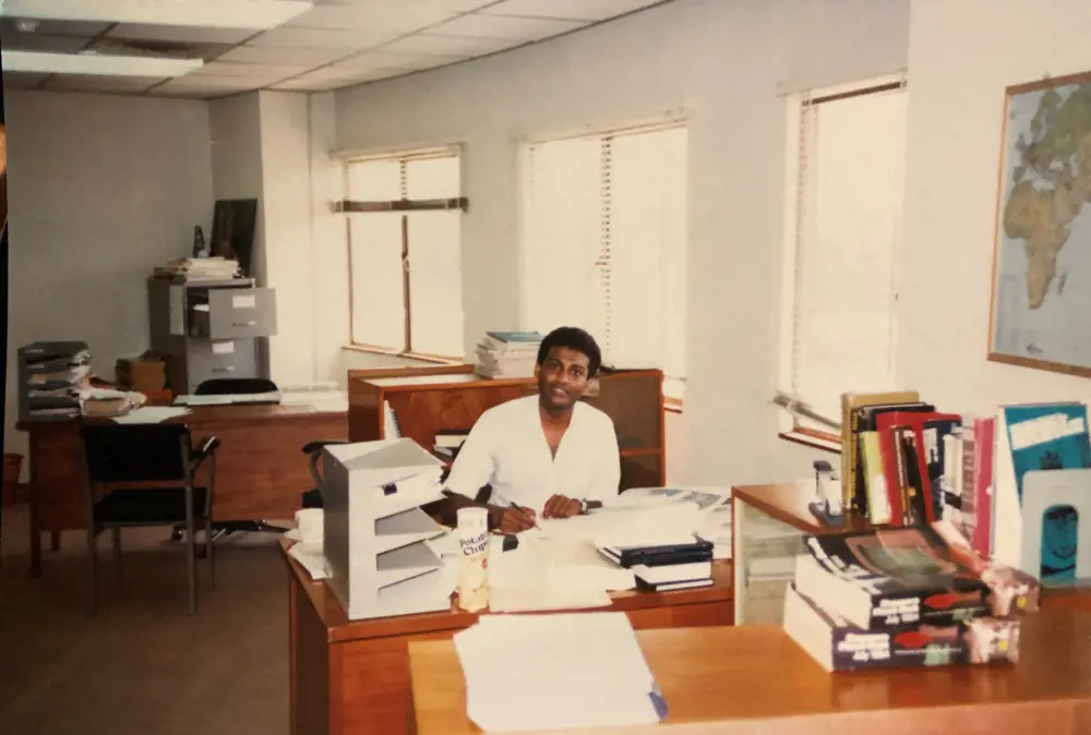Ahilan sitting behind a desk surrounded by papers.