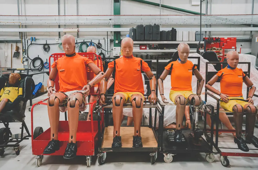 Four crash test dummies in orange t-shirts. Two appear to be the height of an average adult, the other two are closer to the height of an average young person.