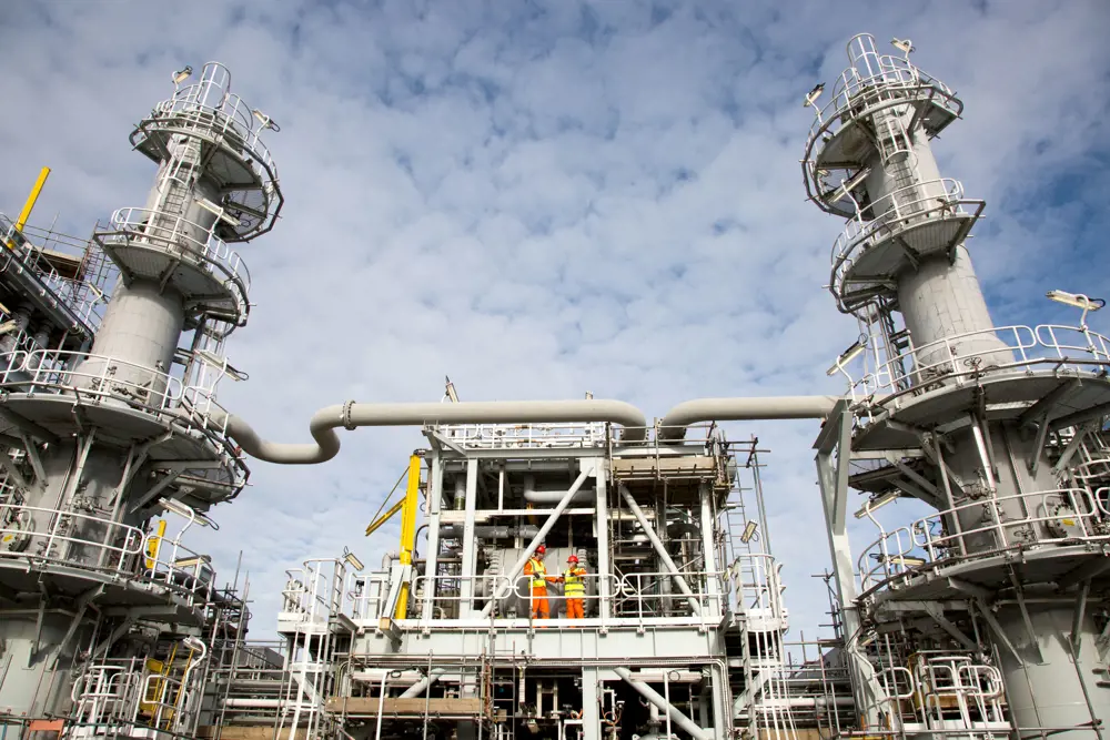 Two construction professionals standing on a platform of the Shetland Gas Plant outside. 