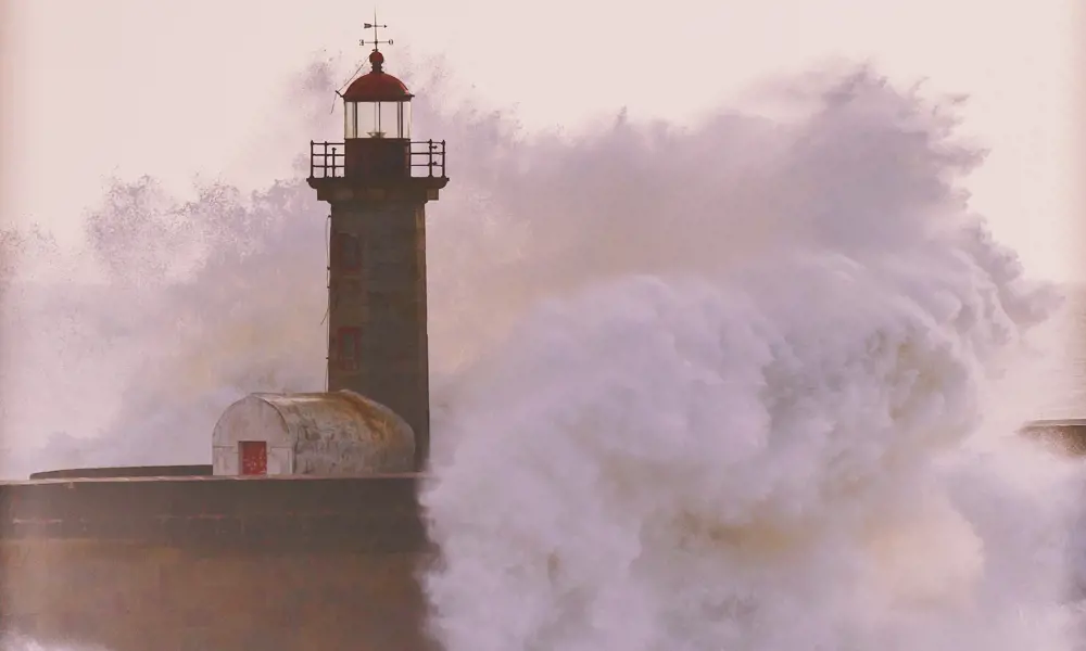 A lighthouse being hit by a huge wave