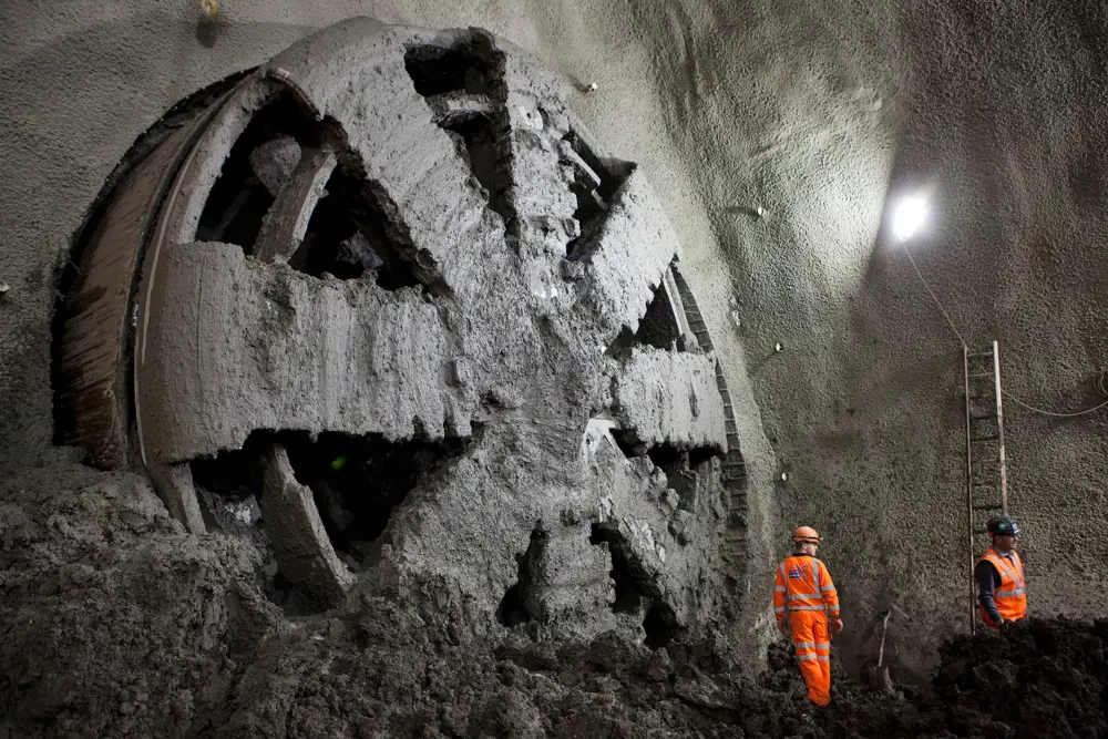Tunnel boring machines excavating a tunnel with two men standing in front.