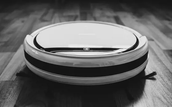 A black and white close up picture of a robotic vacuum.