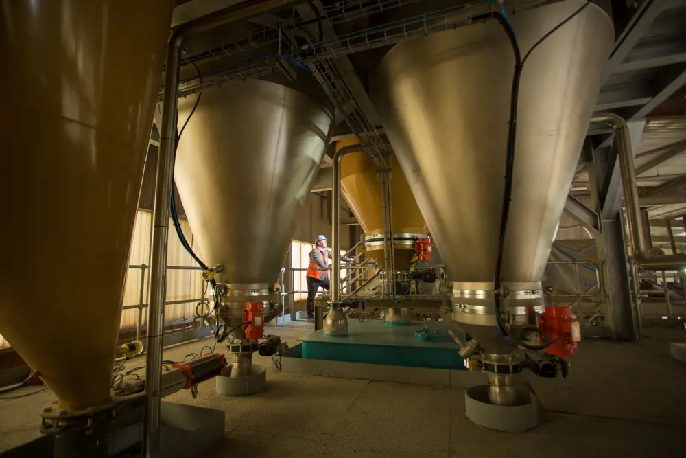 An industrial facility shown with a worker standing among several reactors.