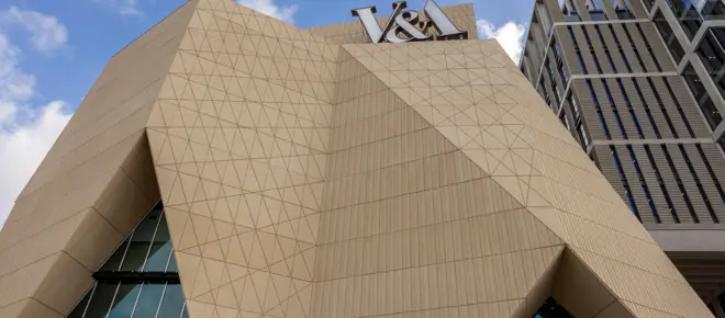 Upward view of V&A East’s sculpted façade and prominent V&A sign.