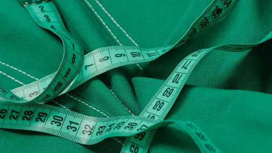 A green tape measure lying on top of green-coloured denim