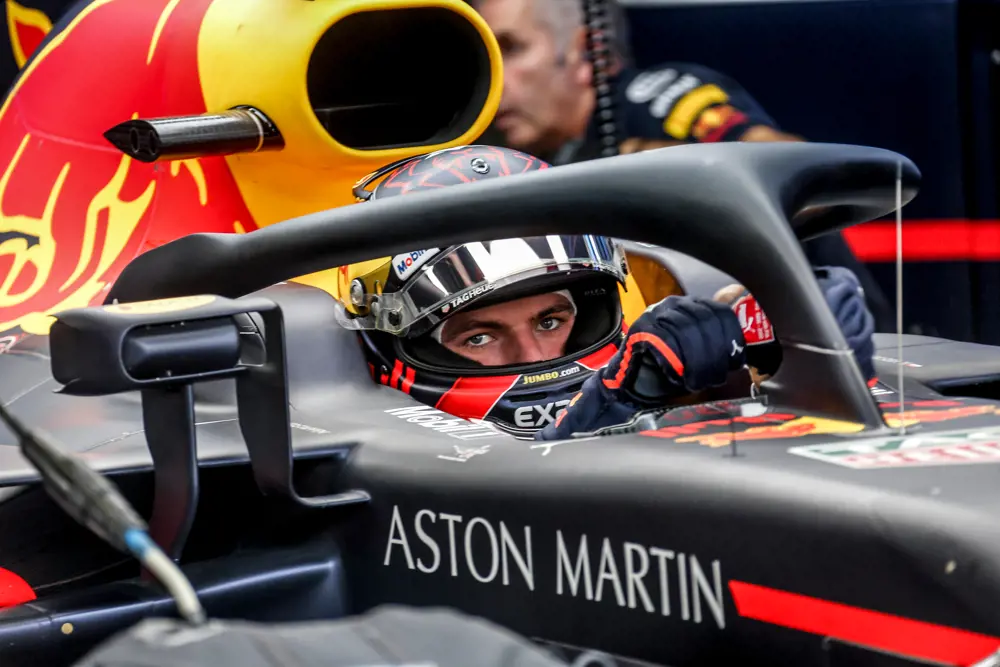 A black titanium protective device protecting a racing driver wearing a helmet in an Aston Martin racecar