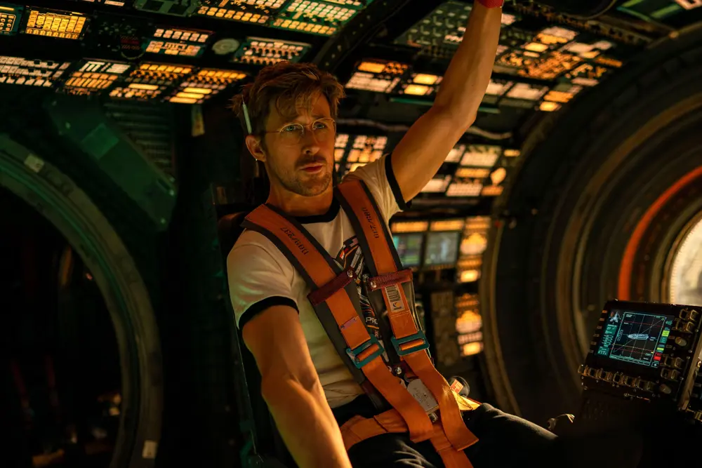 Ryan Gosling as Dr Ryland Grace in Project Hail Mary, strapped into a spacecraft cockpit, surrounded by illuminated control panels during a space mission.
