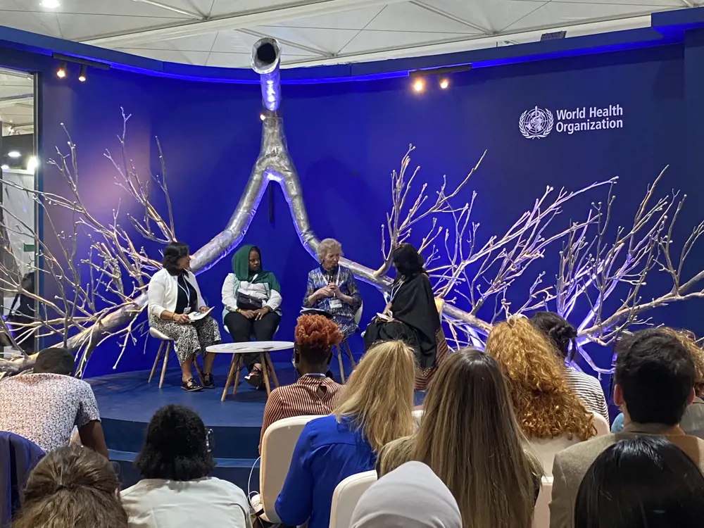 A panel discussion on a blue stage, where three youth environmentalists are in discussion with Mary Robinson.