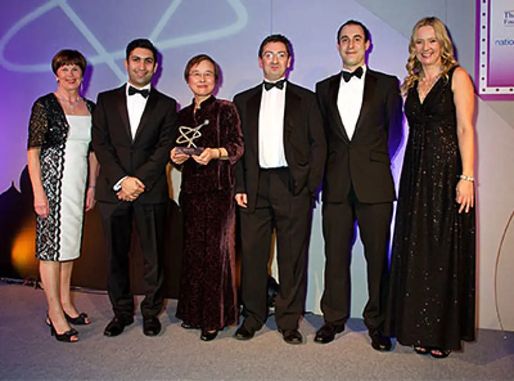 Professor Jiang standing with people at an awards ceremony, holding an award trophy.