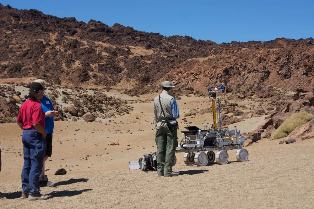 Three people testing the UK prototype Rover Bridget in the dessert landscape of Mount Teide, Tenerife.