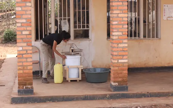 Aakeen Parikh looking at an off-grid washing machine outside a building in Minazi, Rwanda,.