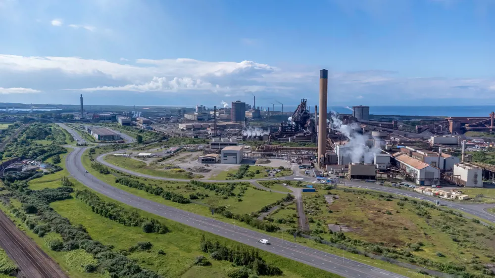 An aerial view of the steelworks on a sunny day at Port Talbot, Wales, with the motorway visible in the foreground